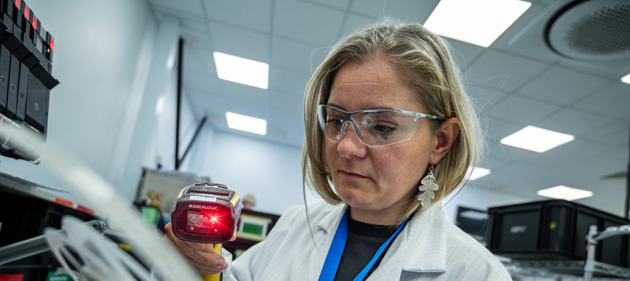 Female in the factory wearing a labcoat and goggles